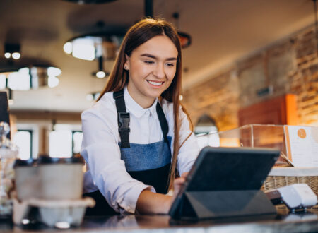 mulher de avental utilizando um chatbot para restaurante através de um tablet em um balcão