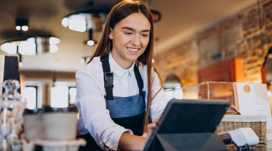 mulher de avental utilizando um chatbot para restaurante através de um tablet em um balcão