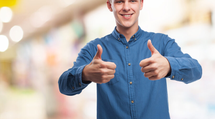 homem branco, cabelos loiros, camisa social da cor azul, levantando os polegares em sinal de aprovação / satisfação dos clientes